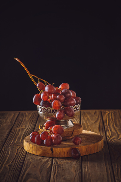 close-up shot of ripe grapes in vintage metal bowl on rustic wooden table on black - Foto, Imagem