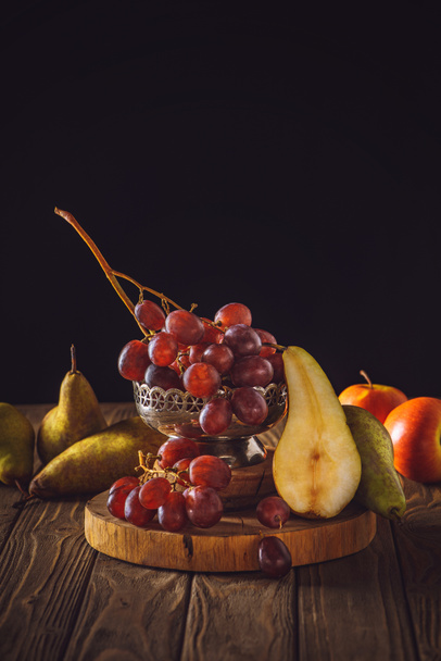 close-up shot of ripe grapes with pears on rustic wooden table on black - Fotó, kép