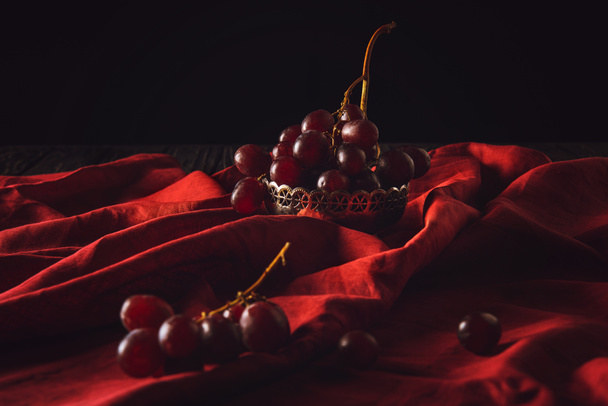 primer plano de uvas en cuenco de metal vintage en rojo cortina en negro
 - Foto, Imagen