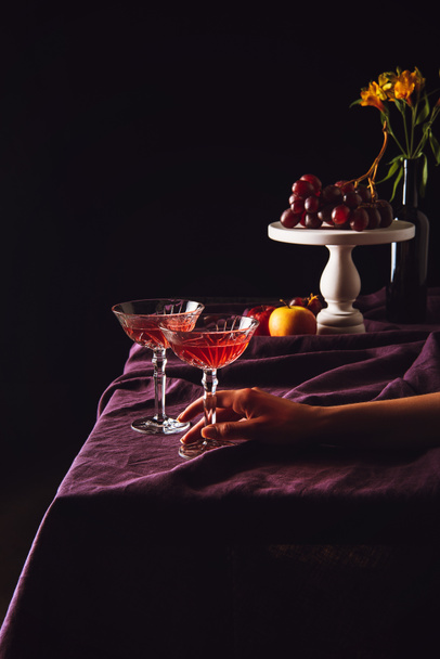 copas vintage de vino de pie con uvas y manzanas en la mesa con cortinas en negro
 - Foto, imagen