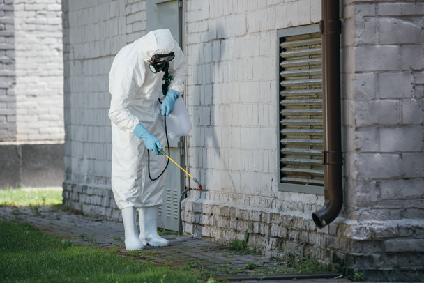 trabajador de control de plagas pulverización de pesticidas con pulverizador en la pared del edificio
 - Foto, Imagen