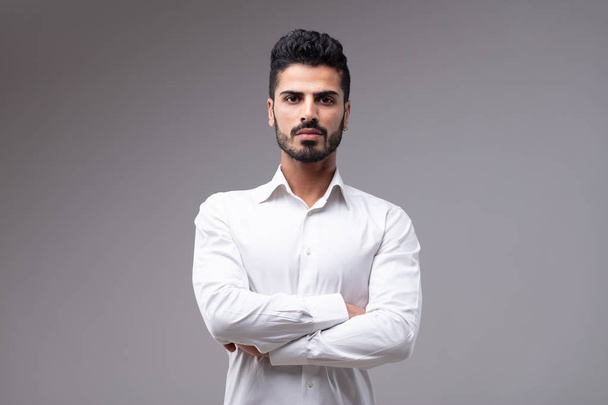 Portrait of young serious bearded man wearing white shirt standing with arms crossed - Photo, Image