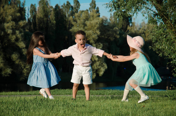 les petits enfants qui jouent sur la pelouse. deux filles et un garçon
 - Photo, image