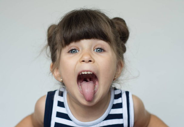 Joyful crazy child gesturing tongues on a white background. - Foto, imagen