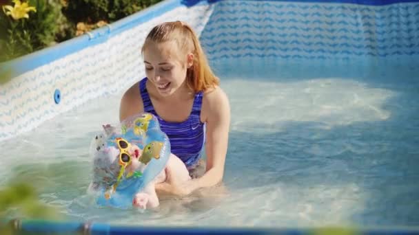 Madre sosteniendo a su hija y ella divirtiéndose en la piscina
 - Metraje, vídeo