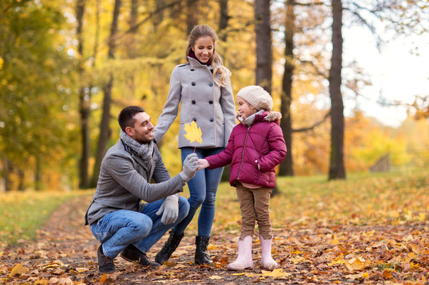 happy family with maple leaf at autumn park - Фото, изображение