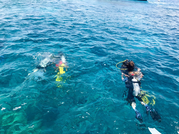 Plongeurs en combinaison imperméable de plongée noire avec des conteneurs en aluminium métal brillant flottent, plongent dans l'eau de mer bleue en vacances, une croisière en mer dans les pays tropicaux
. - Photo, image