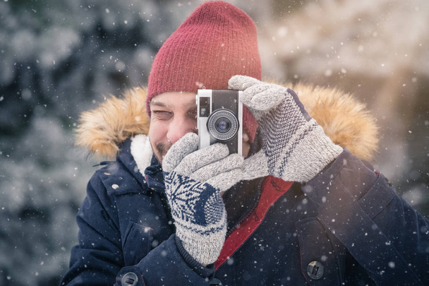 Young man with vintage photo camera in nature. Winter scene background. - Valokuva, kuva