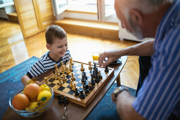 Młody chłopak gra w szachy z dziadek w domu - Zdjęcie, obraz