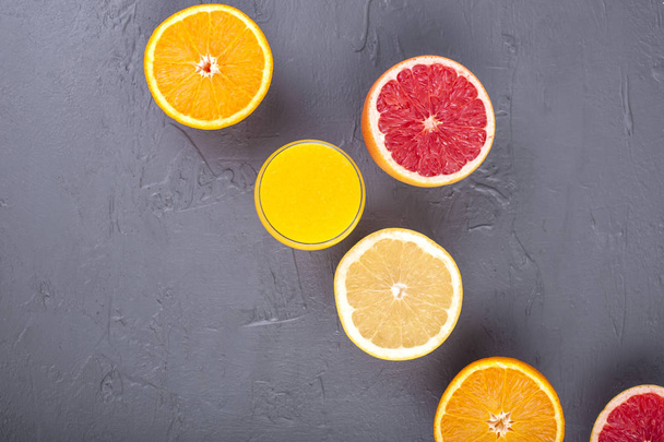 Citrusové plody s různé řezy a šťáva ve skle. Kamenné pozadí. Vitamíny a zdraví v potravinách. Kopírovat prostor - Fotografie, Obrázek