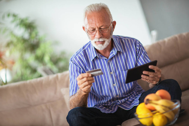 Senior man using credit card for online banking at home - Photo, Image