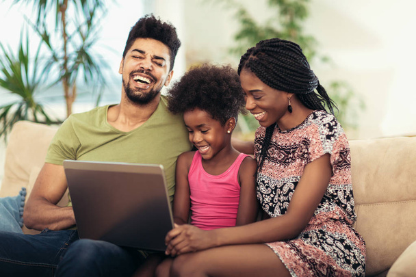 Afro-Amerikaanse familie met laptop in de woonkamer - Foto, afbeelding