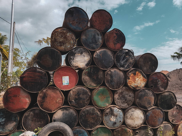 Viejos barriles de colores oxidados de combustibles o productos petrolíferos sobre el fondo del cielo de verano
 - Foto, Imagen