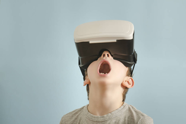 Boy with glasses of virtual reality. Open mouth. Blue background - Фото, изображение
