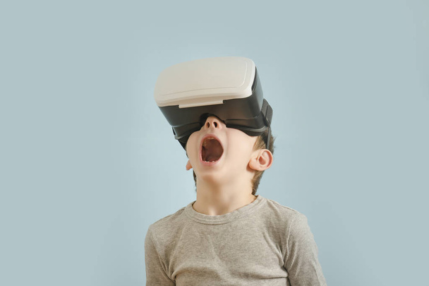 Garçon avec des lunettes de réalité virtuelle. La bouche ouverte. Fond bleu
 - Photo, image