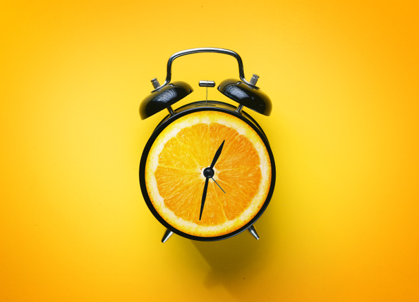 Alarm Clock of Orange Fruit on Yellow Background - Photo, Image