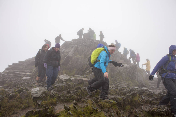 PLLandudno, Wales, UK - MAY 27, 2018 people climbing down from the mountain. Mountaineers descending from the mountain. Group backpacking and hiking down the mountain path - Photo, image