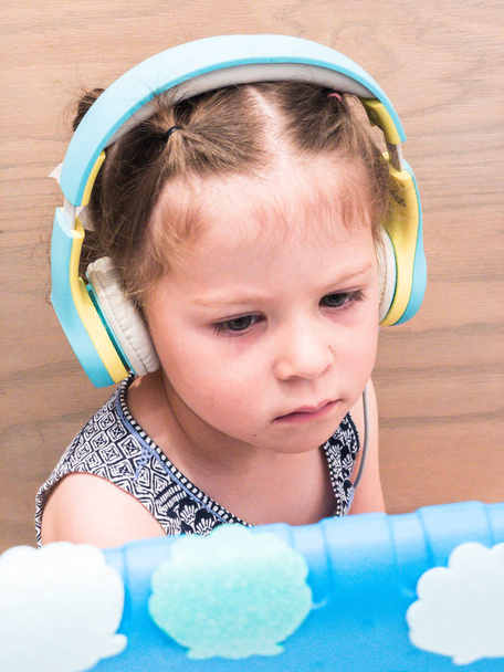 kleines Mädchen mit Headset beim Fernunterricht auf ihrem Tablet. - Foto, Bild
