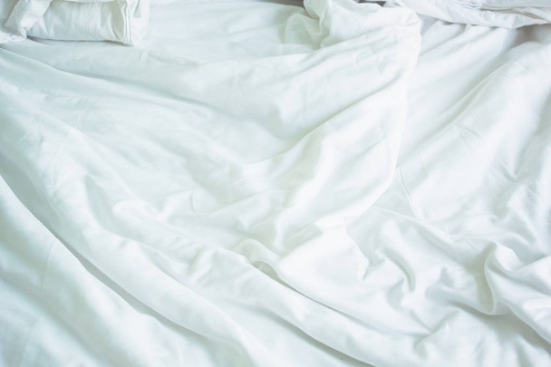 wrinkle messy blanket in bedroom after waking up in the morning, from sleeping in a long night, details of duvet and blanket, an unmade bed in hotel bedroom with white blanket. - Фото, зображення