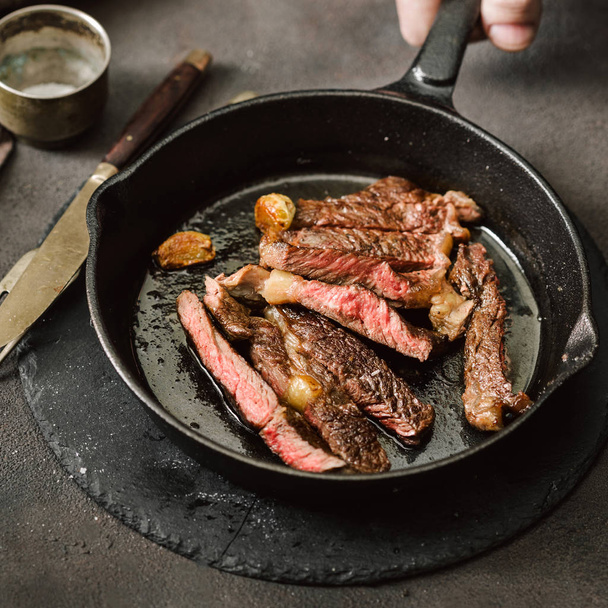 Slices juicy roast beef steak on vintage cast-iron frying pan - 写真・画像