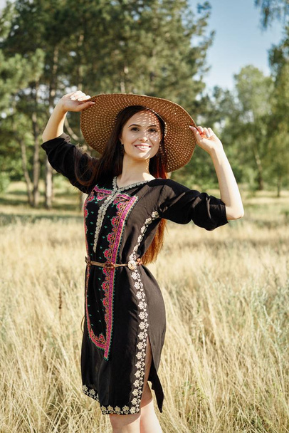 Beautiful young woman in straw hat posing outdoors at sunny summer day  - Photo, image