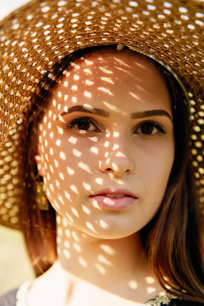 Beautiful young woman in straw hat posing outdoors at sunny summer day  - Fotoğraf, Görsel