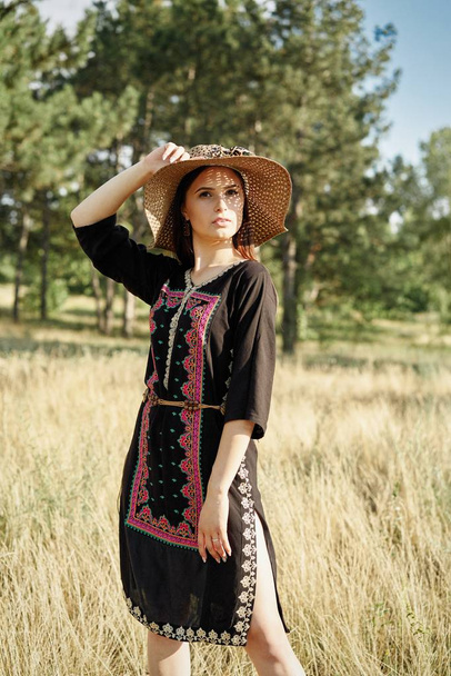 Beautiful young woman in straw hat posing outdoors at sunny summer day  - Valokuva, kuva