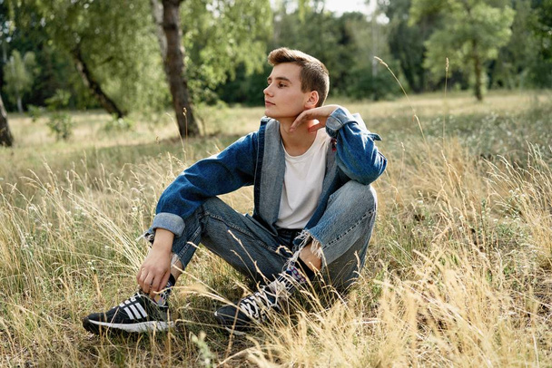 Красивый молодой парень в джинсовой одежде позирует на улице
  - Фото, изображение