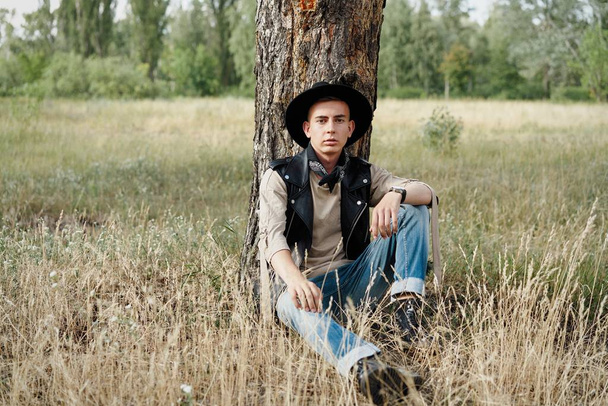 Handsome young guy in casual clothes and stylish hat posing outdoors  - Фото, изображение