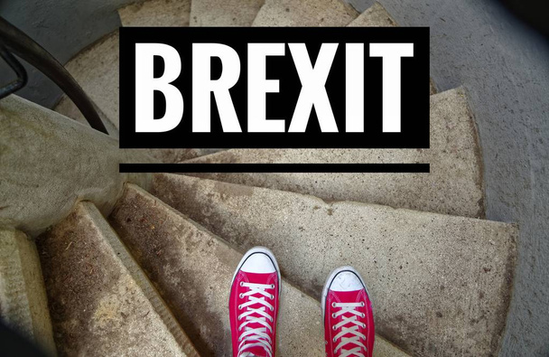 Red sneakers on spiral staircase when going downhill with inscription Brexit symbolizing the withdrawal of Great Britain from the EU - Photo, Image