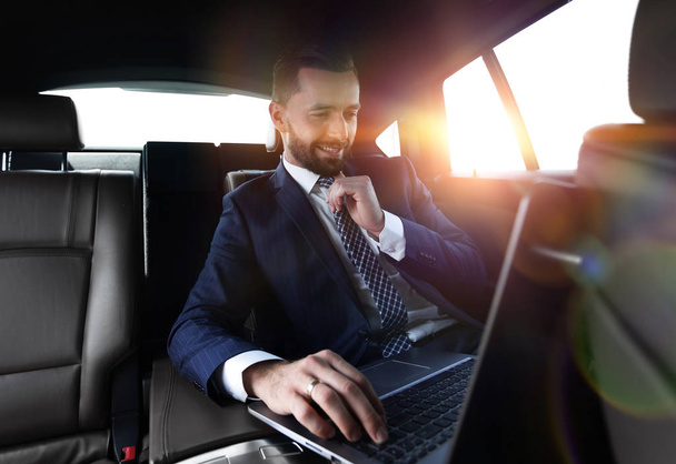 businessman reads information on laptop while sitting in car - 写真・画像