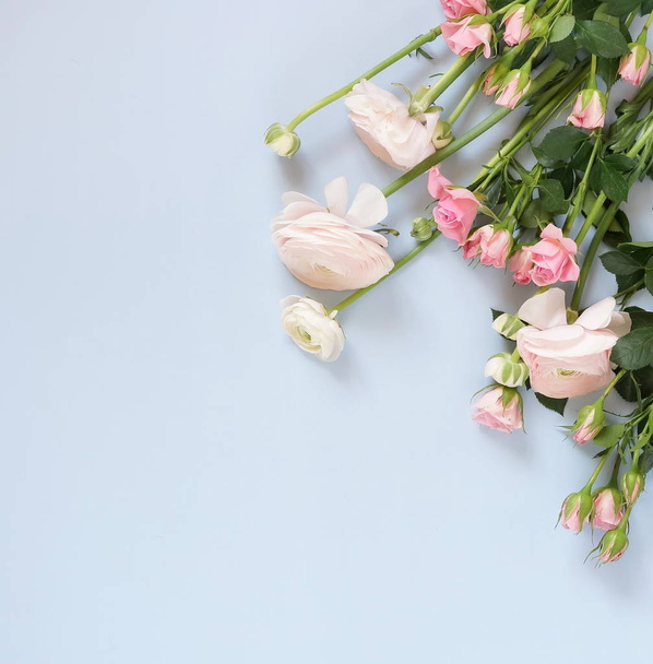 Flowers background. Bouquet of pale pink ranunculus and roses flowers on pale blue background. Top view. Copy space. - Foto, immagini