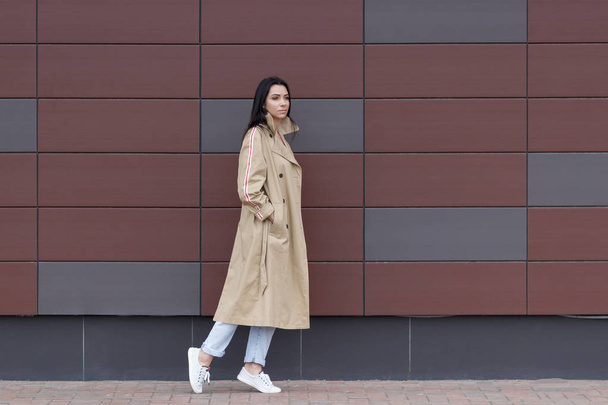Bej bir palto ve kot sokak, yumuşak odak arka plan üzerinde güzel kadın - Fotoğraf, Görsel