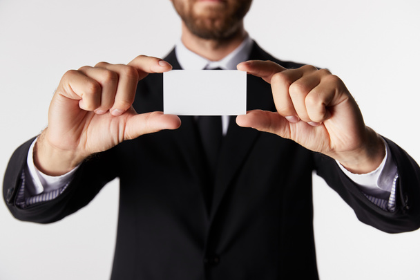 vista parcial del hombre de negocios que presenta la tarjeta de visita en blanco aislado sobre fondo blanco
  - Foto, imagen