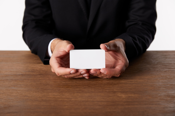 περικομμένη εικόνα του επιχειρηματία δείχνει άδειο επαγγελματική κάρτα στο ξύλινο τραπέζι  - Φωτογραφία, εικόνα