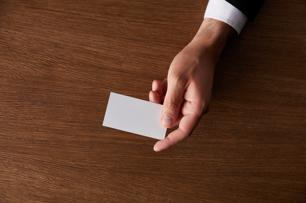 imagen recortada de hombre de negocios dando tarjeta de visita en blanco en la mesa de madera
  - Foto, Imagen