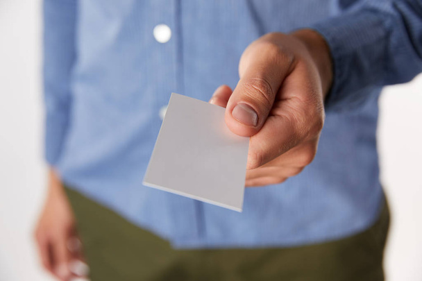 cropped image of businessman giving empty business card on blurred background - 写真・画像