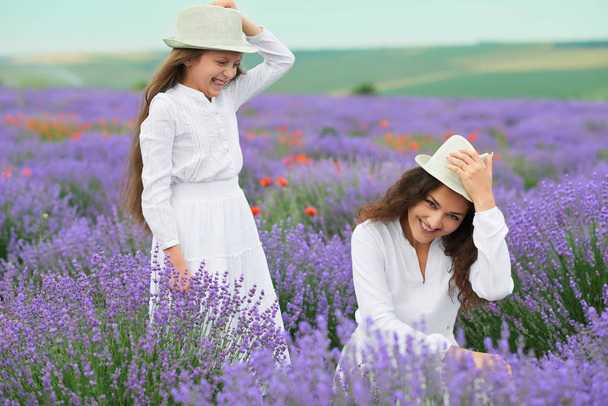 young woman and girl are in the lavender field, beautiful summer landscape with red poppy flowers - Foto, Imagen
