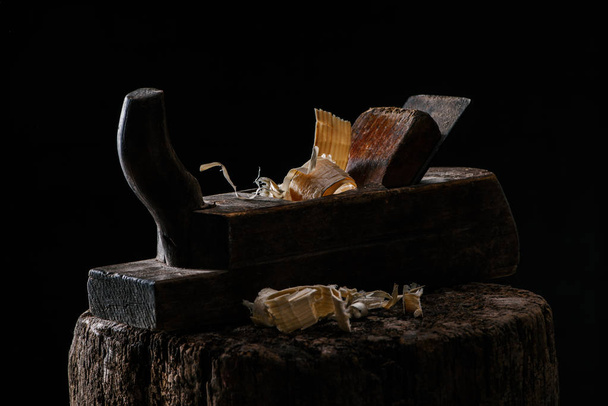  close up view of vintage woodworker plane on wooden stump isolated on black - Foto, Imagem