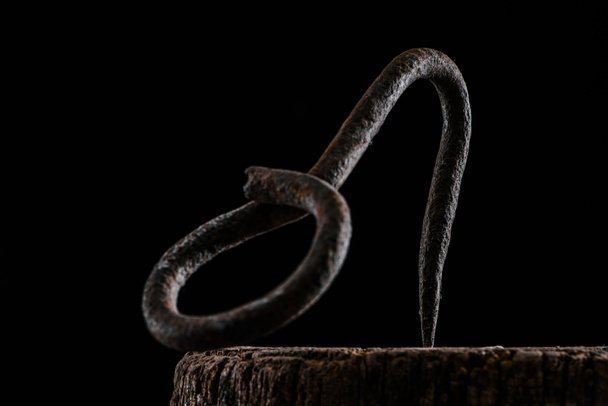  close up view of vintage hook on wooden stump isolated on black - Foto, Imagem