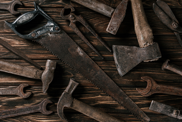 disposición plana con surtido de herramientas oxidadas vintage en la superficie de madera
 - Foto, Imagen