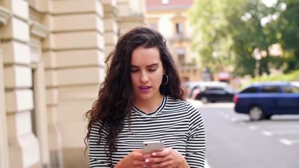 Tyttö käyttää matkapuhelinta kadulla
 - Materiaali, video