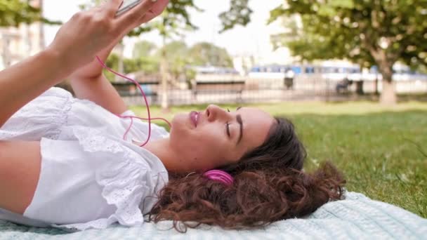 Woman listening to music at the park - Footage, Video