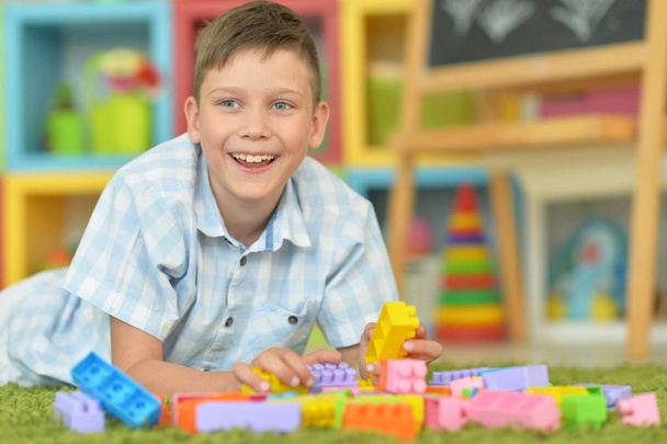 Smiling boy playing with colorful plastic blocks on floor - Foto, imagen