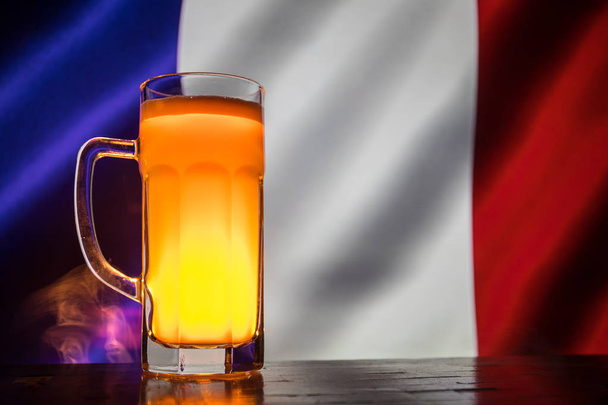 Yaratıcı kavramı. Taze bira masada bir bardak bulanık arka plan üzerinde Fransa bayrağı veya lager bira içmeye hazır kadeh. Uzay kopyalayın. Seçici odak - Fotoğraf, Görsel