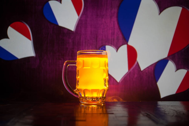 kreatives Konzept. Pint von frischem Bier auf dem Tisch mit verschwommener Frankreich-Flagge auf dem Hintergrund oder einem Glas Lagerbier, das zum Trinken bereit steht. Kopierraum. Selektiver Fokus - Foto, Bild