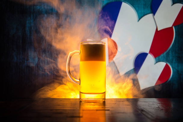Creatief concept. Pint vers bier op tafel met wazig vlag van Frankrijk op achtergrond of glas pils bier klaar voor drankje. Kopieer ruimte. Selectieve aandacht - Foto, afbeelding