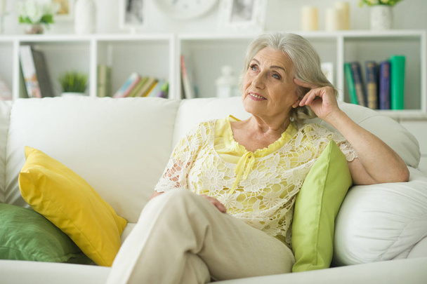 Beautiful senior woman sitting on sofa at home - Фото, зображення