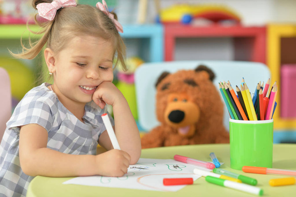  cute little girl drawing with felt pen while sitting at table in her room - Photo, image