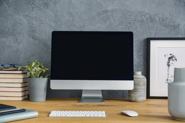Mockup of desktop computer on wooden desk with plant in grey workspace interior. Real photo - Φωτογραφία, εικόνα